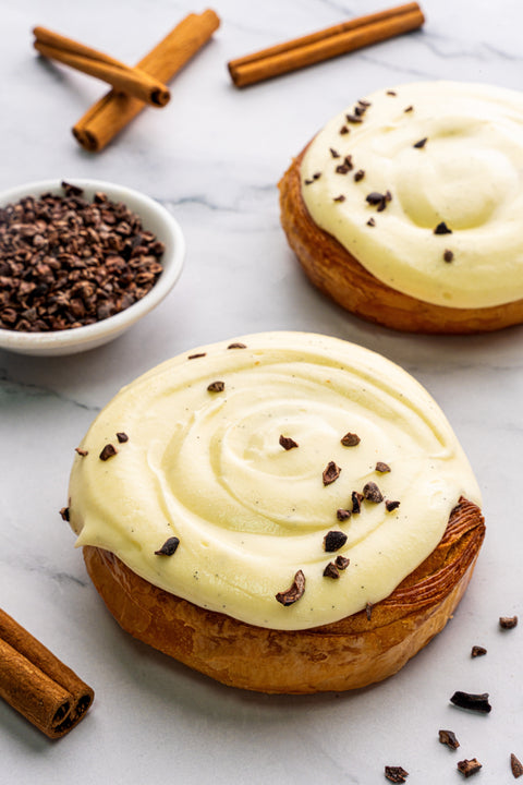 Image of a luscious Cinnamon Roll from Laura's Home Bakery, generously topped with cinnamon cream, showcasing its golden-brown exterior and soft, sweet interior.
