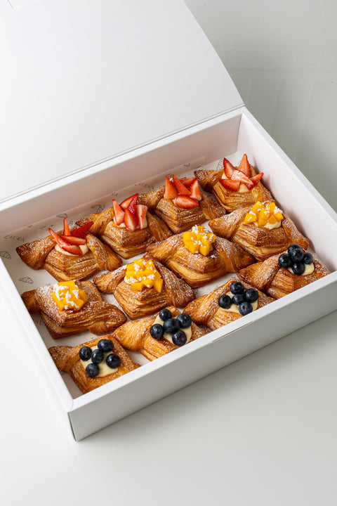 Box of pastries with fruit toppings on a light background