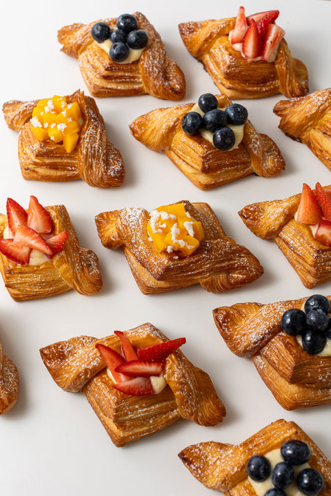 Small pastries with fruit toppings on a white surface