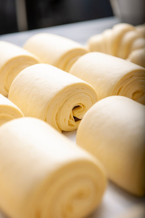 Image of a Pain Au Chocolat - Frozen 6-Pack from Laura's Home Bakery, showcasing their convenience and buttery, flaky layers with a luscious core of rich, velvety chocolate.