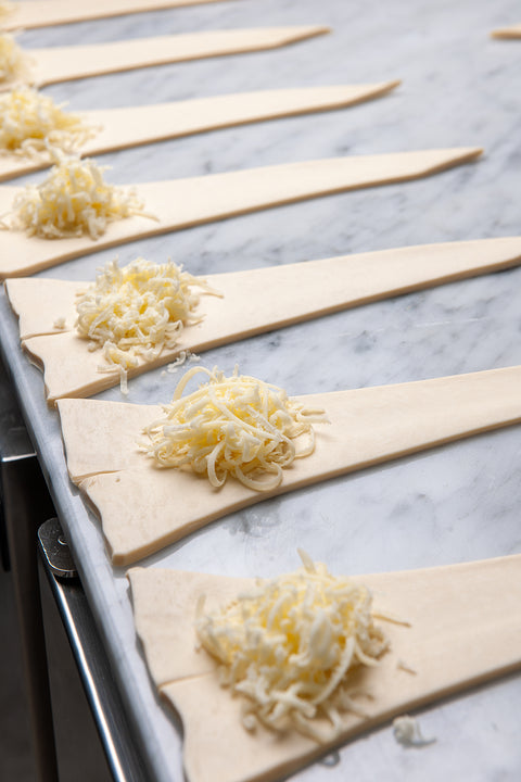 Croissants in the process of being prepared, with skilled hands expertly shaping the dough into classic triangular forms.