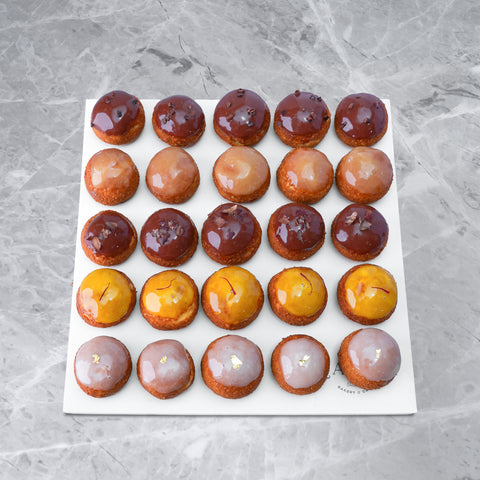 An array of baked pastries arranged on a marble surface with a reflective background.