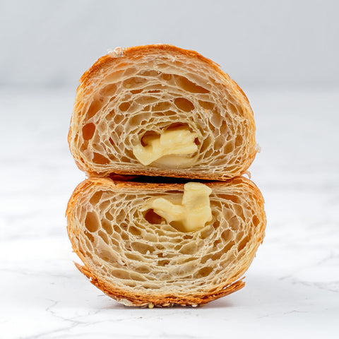 cross section Image of an Emmental Croissant from Laura's Home Bakery, showcasing its flaky layers and a generous filling of Emmental cheese, perfectly baked to golden perfection.