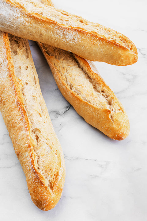 Image of a Traditional Sourdough Baguette from Laura's Home Bakery, showcasing its rustic crust and chewy, tangy interior.