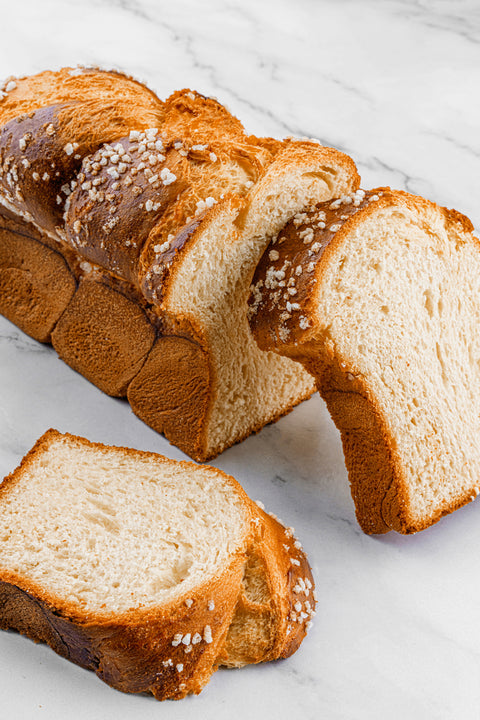 Image of a sliced Sugar Brioche Braid Loaf, showcasing its rich, golden crust and soft, buttery interior, with subtle sugar pearls.