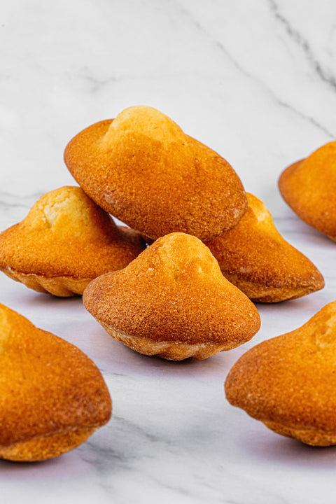 close up Image of Madeleines from Laura's Home Bakery, showcasing their delicate, shell-shaped form and a tender crumb with a hint of citrus zest