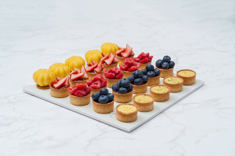 Image of a 25-piece assortment of Mini Mix Tarts from Laura's Home Bakery, showcasing their vibrant fruit fillings and golden-brown, buttery crusts.