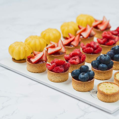 Closeup Image of a 25-piece assortment of Mini Mix Tarts from Laura's Home Bakery, showcasing their vibrant fruit fillings and golden-brown, buttery crusts.