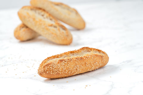 Single Image of a Mini White Sesame Sourdough Baguette from Laura's Home Bakery, showcasing its rustic exterior adorned with a delicate sprinkle of white sesame seeds