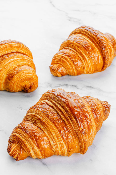 Image of a Plain Croissant from Laura's Home Bakery, showcasing its flaky layers and golden, buttery crust.