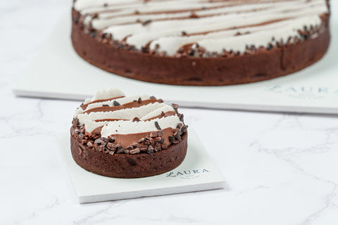 Close up Image of a mini Triple Chocolate Tart with White Vanilla Ganache and Chocolate Whipped Cream from Laura's Home Bakery, showcasing its luxurious toppings and decadent chocolate layers.