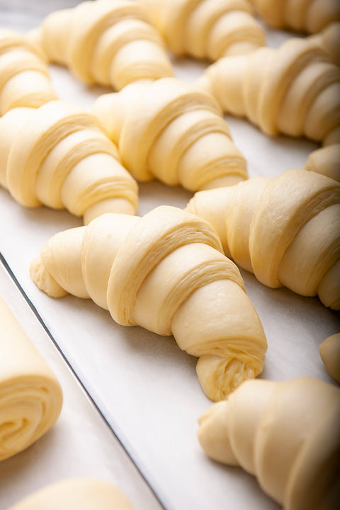 Uncooked croissants on a baking sheet, awaiting their transformation into golden, flaky delights.