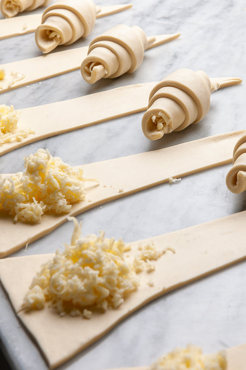 A baker carefully rolling out croissant dough, a crucial step in creating the signature flaky texture