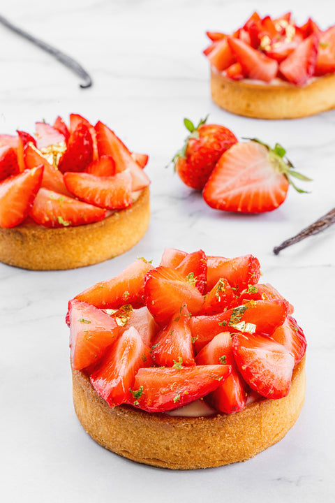 Close-up view of a mini Strawberry Tart from Laura's Home Bakery, showcasing the meticulous arrangement of fresh, juicy strawberries on a petite, golden crust.