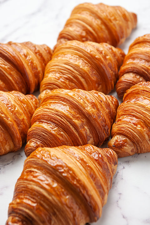 Close-up view of freshly baked Plain Pure Butter Croissants from Laura's Home Bakery, highlighting their golden, flaky exterior and inviting buttery aroma.